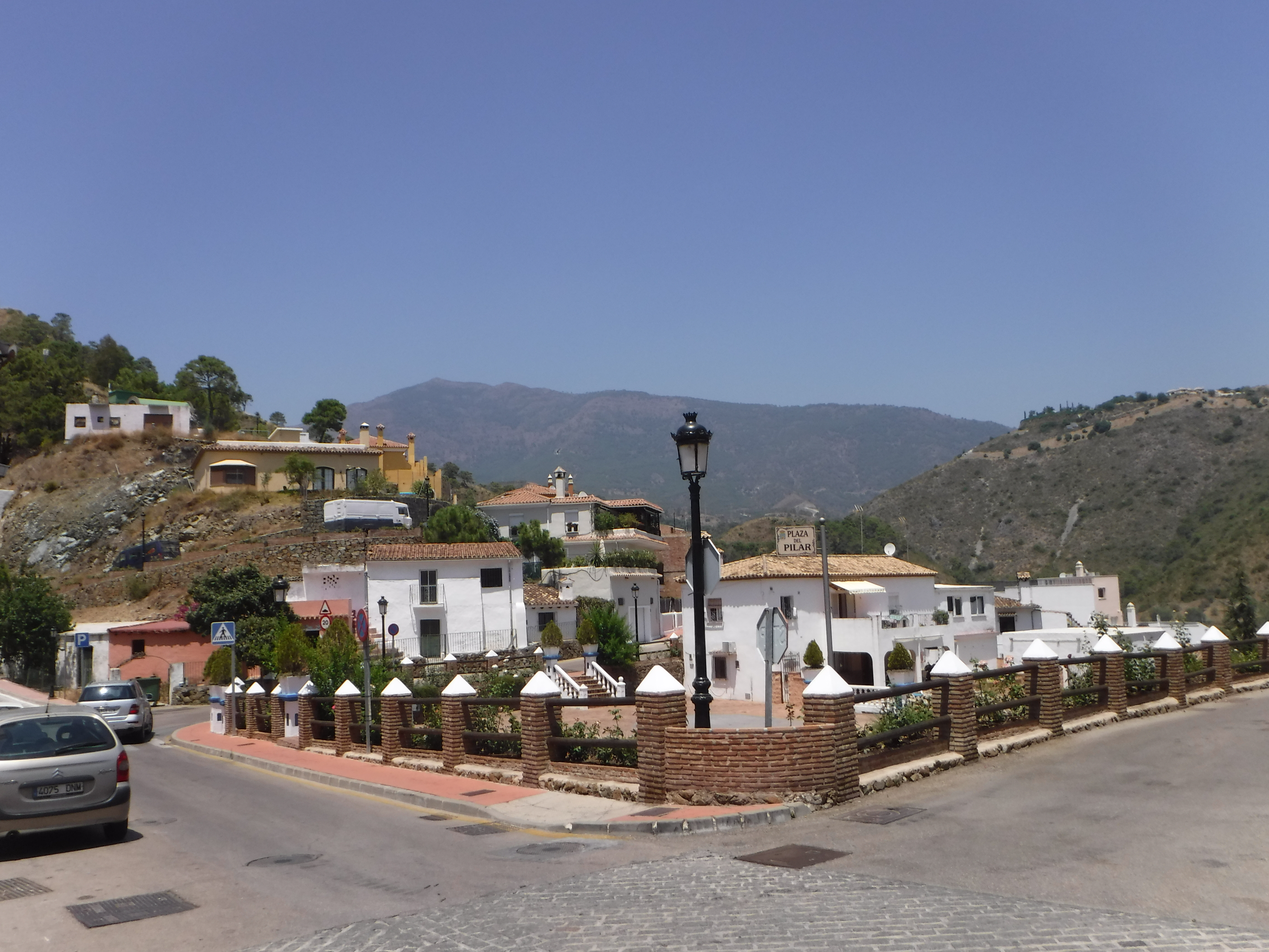 Straßenszene in Benahavís, Spanien, mit weißen Häusern und Bergen im Hintergrund.